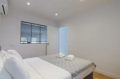 a white bedroom with a bed with two towels on it at Athens Trikoupi Suite B3 in Athens