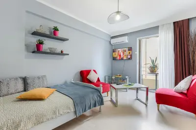 a bedroom with a bed and a red chair at Thanasis Family Apartment in Athens