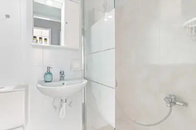 a white bathroom with a sink and a shower at Thanasis Family Apartment in Athens