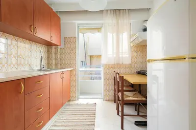a kitchen with wooden cabinets and a table and a refrigerator at Thanasis Family Apartment in Athens