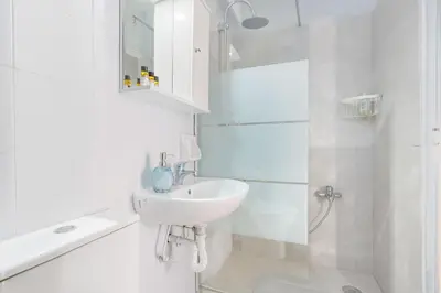 a white bathroom with a sink and a shower at Thanasis Family Apartment in Athens