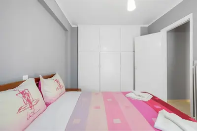 a bedroom with a bed with pink and purple pillows at Thanasis Family Apartment in Athens