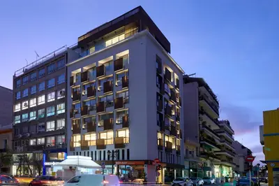 a tall building with cars parked in front of it at Twinn Downtown Piraeus, Santikos Collection in Piraeus