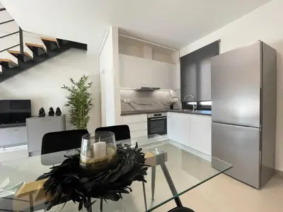 a kitchen with a table and a stainless steel refrigerator at Athenean Modern Escape near Marina Flisvos in Athens