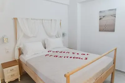 a bedroom with a white bed with a sign on it at Golden Star Praxitelous in Agia Marina Aegina