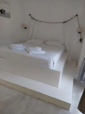 a bedroom with a white bed with a hanging bed frame at Golden Star Praxitelous in Agia Marina Aegina