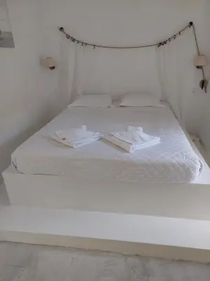 a white bed with white sheets and towels on it at Golden Star Praxitelous in Agia Marina Aegina