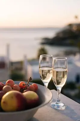 two glasses of white wine next to a bowl of fruit at Villa Mare Nostrum Sounio in Sounio
