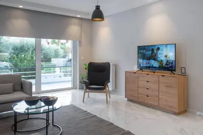 a living room with a tv and a couch and a table at Glyfada Diamond Residence - 3 Master Bedrooms in Athens