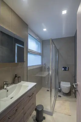 a bathroom with a sink and a shower and a toilet at Glyfada Diamond Residence - 3 Master Bedrooms in Athens