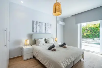 a white bedroom with a large bed and a window at Glyfada Diamond Residence - 3 Master Bedrooms in Athens