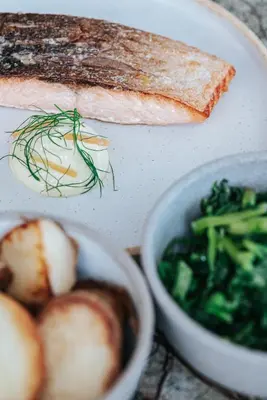 a plate of food with fish and a bowl of vegetables at Athenarum Portus Life & Style Hotel in Piraeus