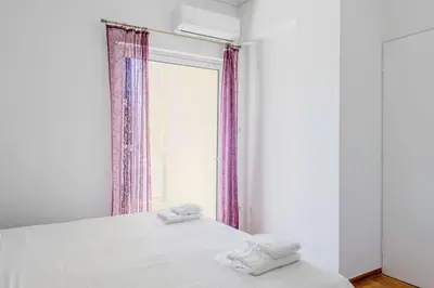 a bedroom with a white bed with a window at Charming 2 Bdrm Glyfada Getaway in Athens