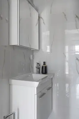 a white bathroom with a sink and white cabinets at Charming 2 Bdrm Glyfada Getaway in Athens