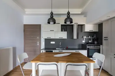 a kitchen with a wooden table and white chairs at Stratum Apartment by LobbySquare in Athens