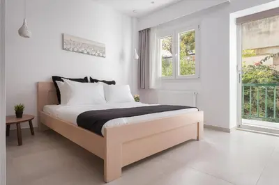 a bedroom with a bed with white walls and a window at Acropolis Urban Life in Athens