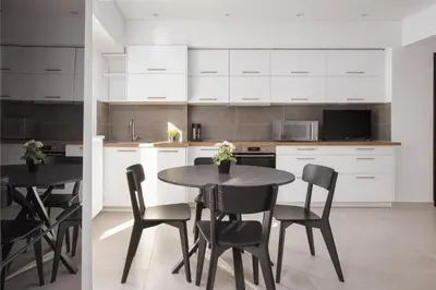 a kitchen with white cabinets and a black table and chairs at Acropolis Urban Life in Athens