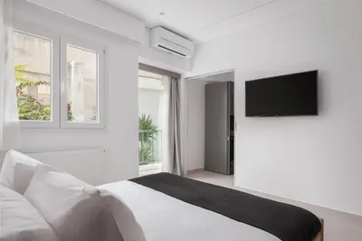 a white bedroom with a bed and a flat screen tv at Acropolis Urban Life in Athens