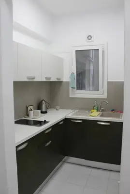 a kitchen with black and white cabinets and a sink at Cozy apartment in Athens center in Athens
