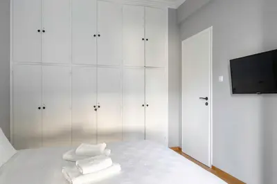a white bedroom with white cabinets and a bed with towels at Stylish Central Cozy one BEDROOM Apartment in Athens