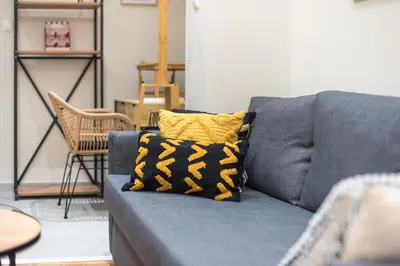 a blue couch with a yellow and black pillow on it at Exclusive Mavili Suite by CloudKeys in Athens