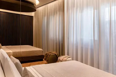 a bedroom with two beds and a window with curtains at Bullet Athens in Athens
