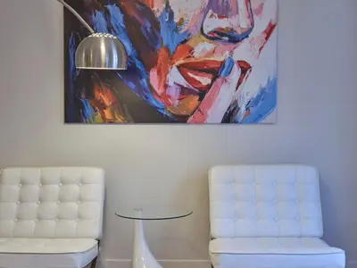 a table and a chair in a room with a painting at Quiet, central 2bd Apt, Kolonaki in Athens