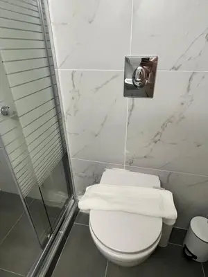 a bathroom with a toilet and a shower with towels at Metropolitan Complex Apartment-next to Metropolitan Hospital,Karaiskaki,Sef in Piraeus