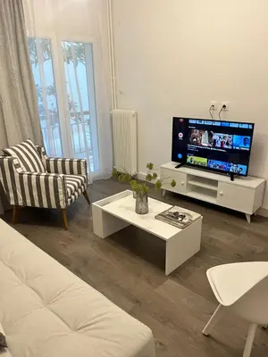 a living room with a tv and a couch and a table at Metropolitan Complex Apartment-next to Metropolitan Hospital,Karaiskaki,Sef in Piraeus