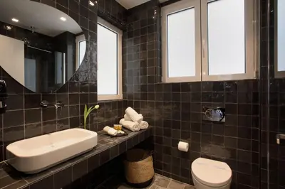 a black tiled bathroom with a sink and a toilet at Happiness Luxury Central Apartment in Athens