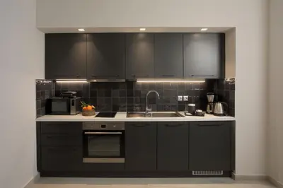 a kitchen with black cabinets and a sink at Happiness Luxury Central Apartment in Athens