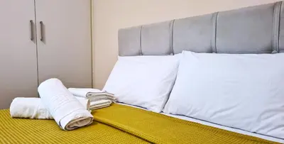 a bed with white sheets and pillows on it at Apartment in Athens, Kallithea in Athens