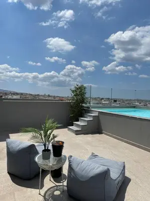 a patio with a pool and chairs and a table at Luxury Maisonette with Shared Pool in Athens