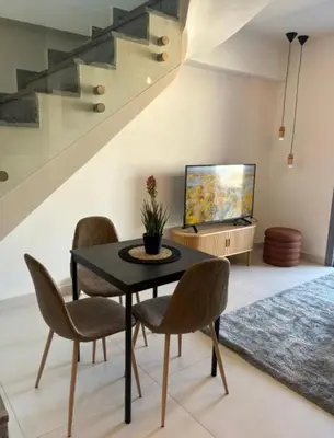 a dining room with a table and chairs and a television at Luxury Maisonette with Shared Pool in Athens