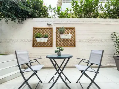 two chairs and a table with two plants on a fence at Cozy studio near Flisvos Marina in Athens