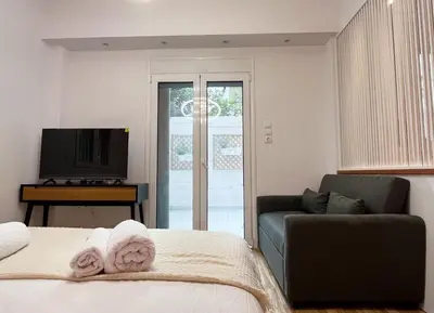 a bedroom with a bed and a couch and a television at Cozy studio near Flisvos Marina in Athens