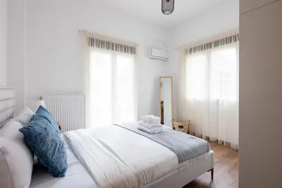 a white bedroom with a bed and two windows at Alex 2 Bedroom Apartment in Athens in Athens