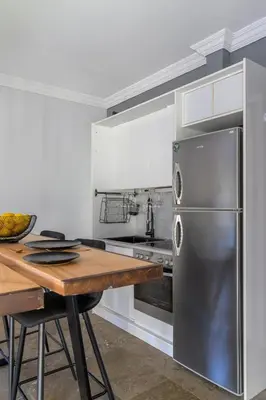a kitchen with a wooden table and a stainless steel refrigerator at Eclipse Riviera Cinema in Athens