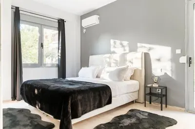 a bedroom with a white bed with a black blanket on it at Eclipse Riviera Cinema in Athens