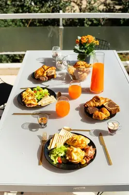 a white table with plates of food and glasses of orange juice at Eclipse Riviera Cinema in Athens
