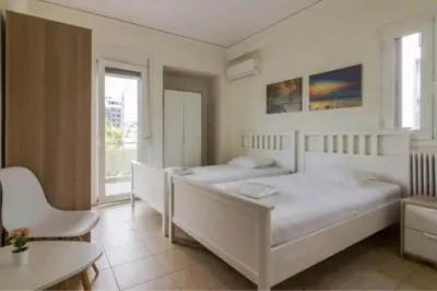 a bedroom with two beds and a table and a chair at Spacious 3bdr apart w/balcony-5 mins to acropolis in Athens