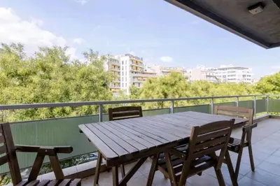 a wooden table and chairs on a balcony at Spacious 3bdr apart w/balcony-5 mins to acropolis in Athens