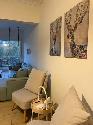 a living room with a couch and a table with a chair at Spacious 3bdr apart w/balcony-5 mins to acropolis in Athens