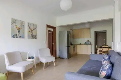 a living room with a blue couch and white chairs at Spacious 3bdr apart w/balcony-5 mins to acropolis in Athens
