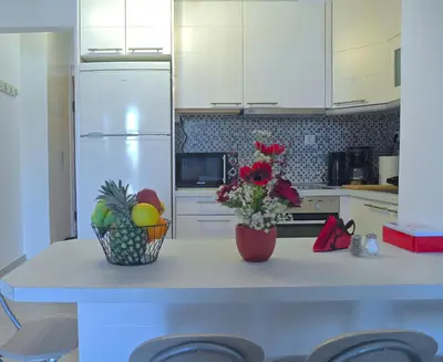 a kitchen with a counter with a vase of flowers at Seaside Bliss in Varkiza - Dreamy Balcony with Stunning Sea Views in Varkiza