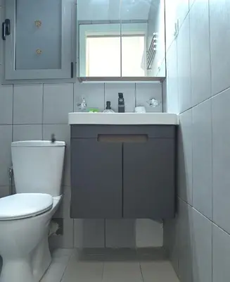 a bathroom with a white toilet and a sink at Seaside Bliss in Varkiza - Dreamy Balcony with Stunning Sea Views in Varkiza