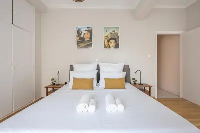 a white bed with two pairs of slippers on it at Spacious 2BDs Apt With Acropolis View In Center in Athens