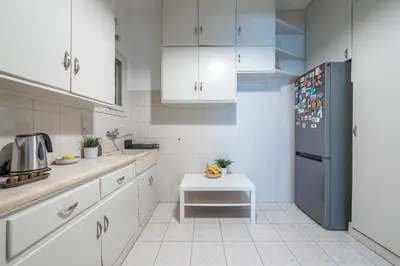 a kitchen with white cabinets and a black refrigerator at Spacious 2BDs Apt With Acropolis View In Center in Athens