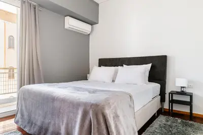a bedroom with a large bed with white sheets and a window at Eclipse Glyfada Beach in Athens