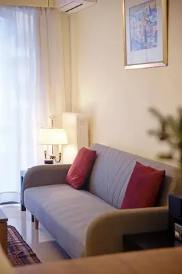 a living room with a couch with two red pillows at Athens Faliro Beach Residence, close to city center in Athens